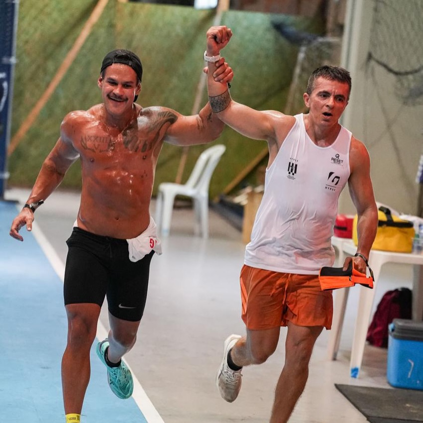 Dois participantes comemoram juntos ao concluir uma prova híbrida